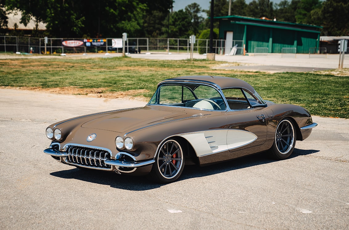 Rear View of a Brown 1958 Chevy Corvette in a Parking Lot on a Sunny Day with a White Truck in the Distance