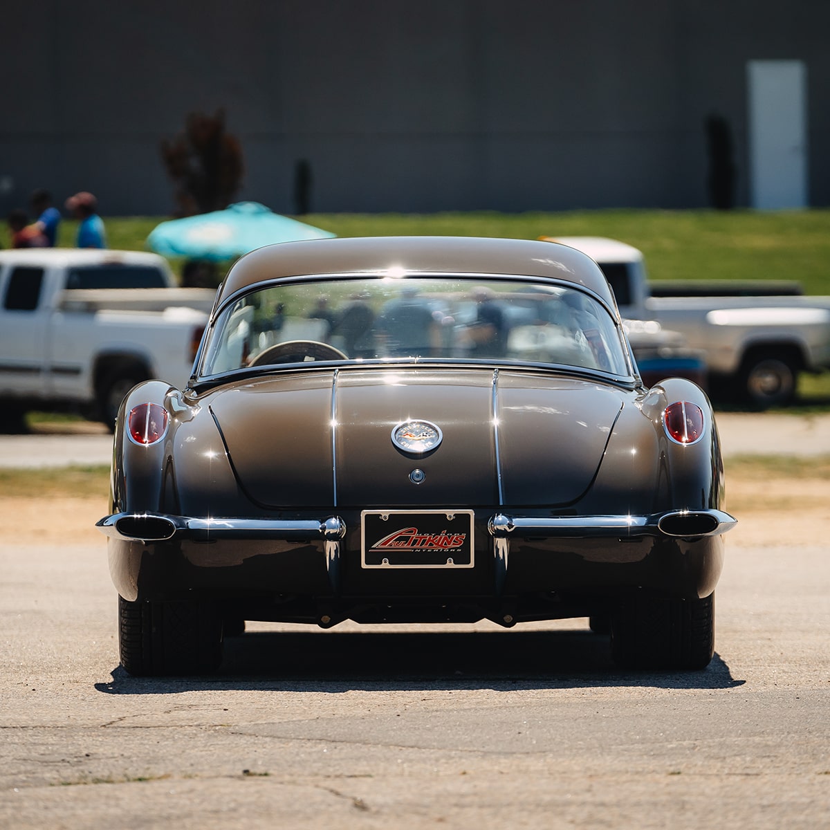 Rear View of a Brown 1958 Chevy Corvette in a Parking Lot on a Sunny Day with a White Truck in the Distance