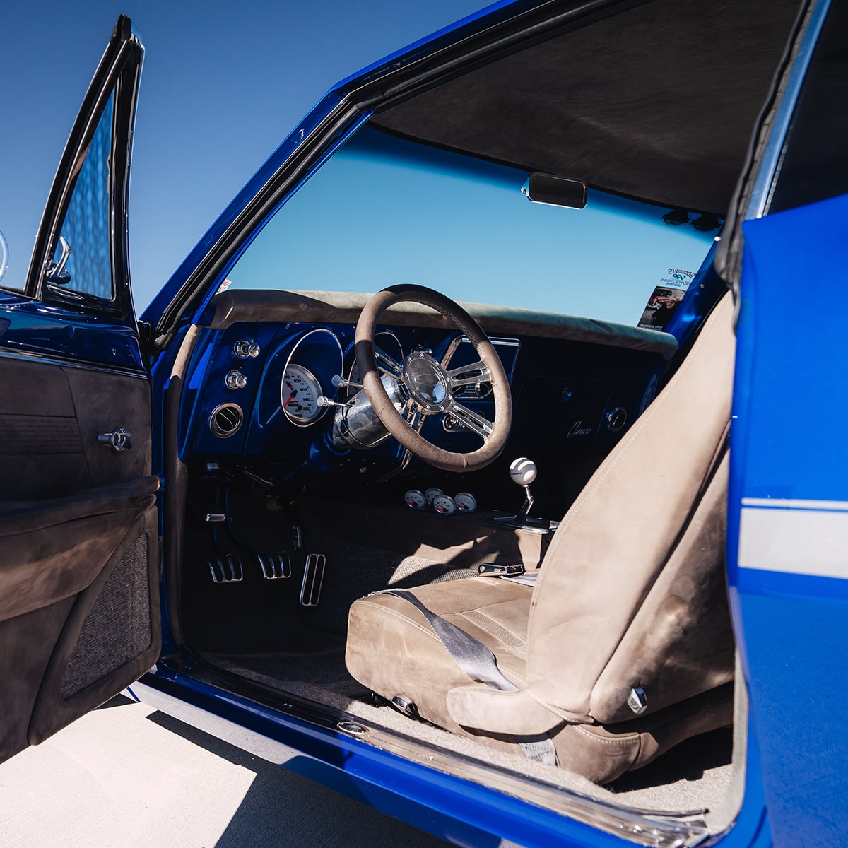 View of the Driver's Side Interior and Seat of a Blue 1967 Chevy Camaro SS Seen Through the Open Driver's Side Door