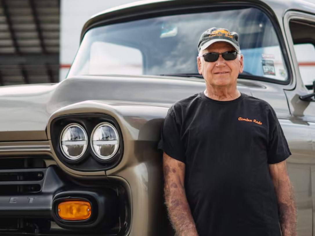 A Man Wearing a Black T-Shirt and Shades Poses in Front of a Vintage Chevrolet Pickup Truck