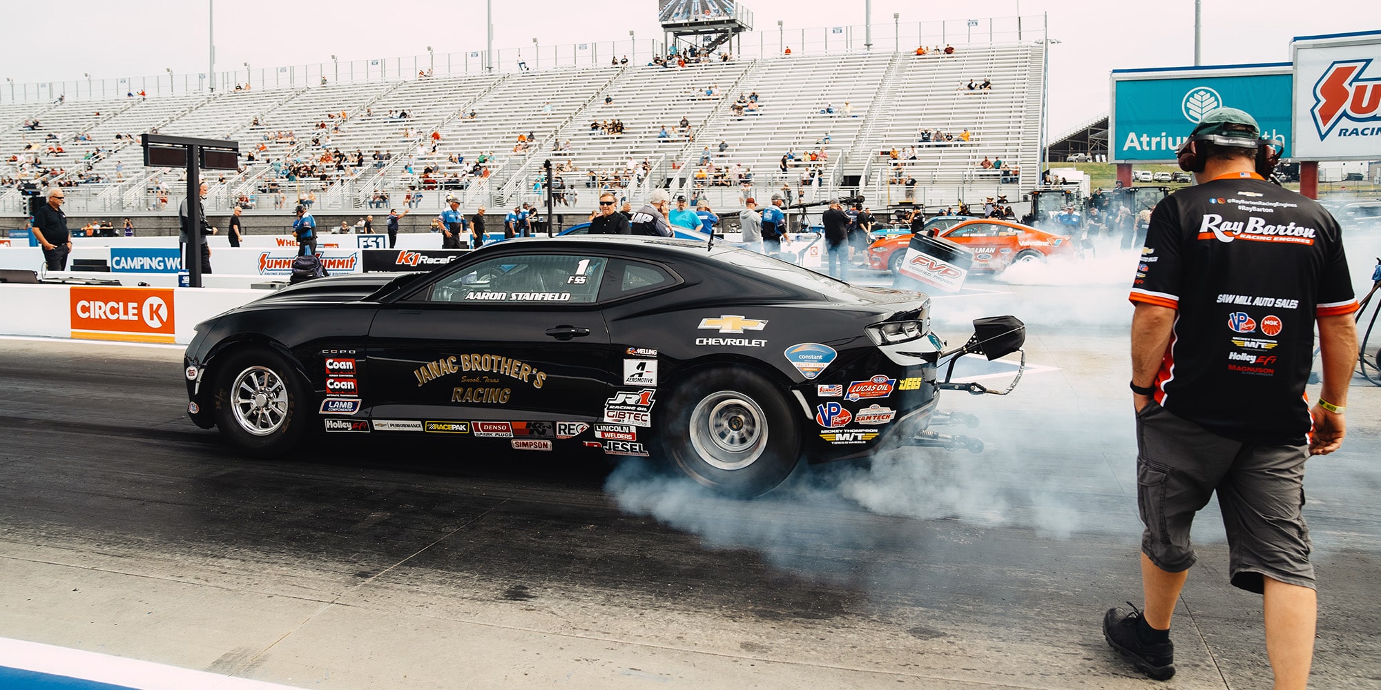 Camaro Racer Spinning Out Back Tires with Crew Walking Towards the Vehicle
