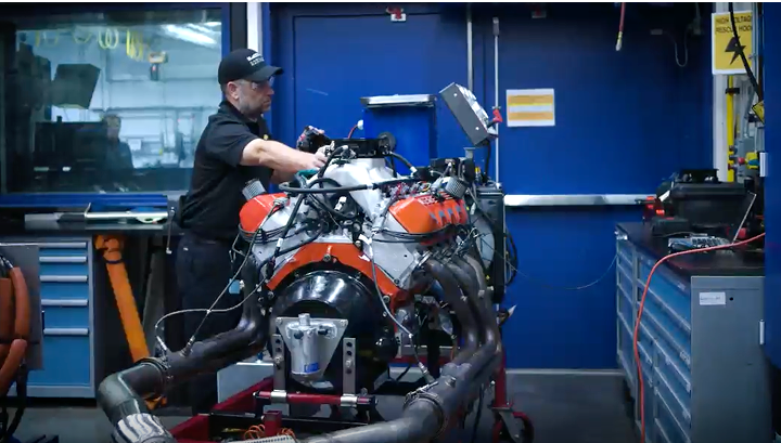 A Person Is Seen Carrying a Heavy Part to the Engine of a Vehicle