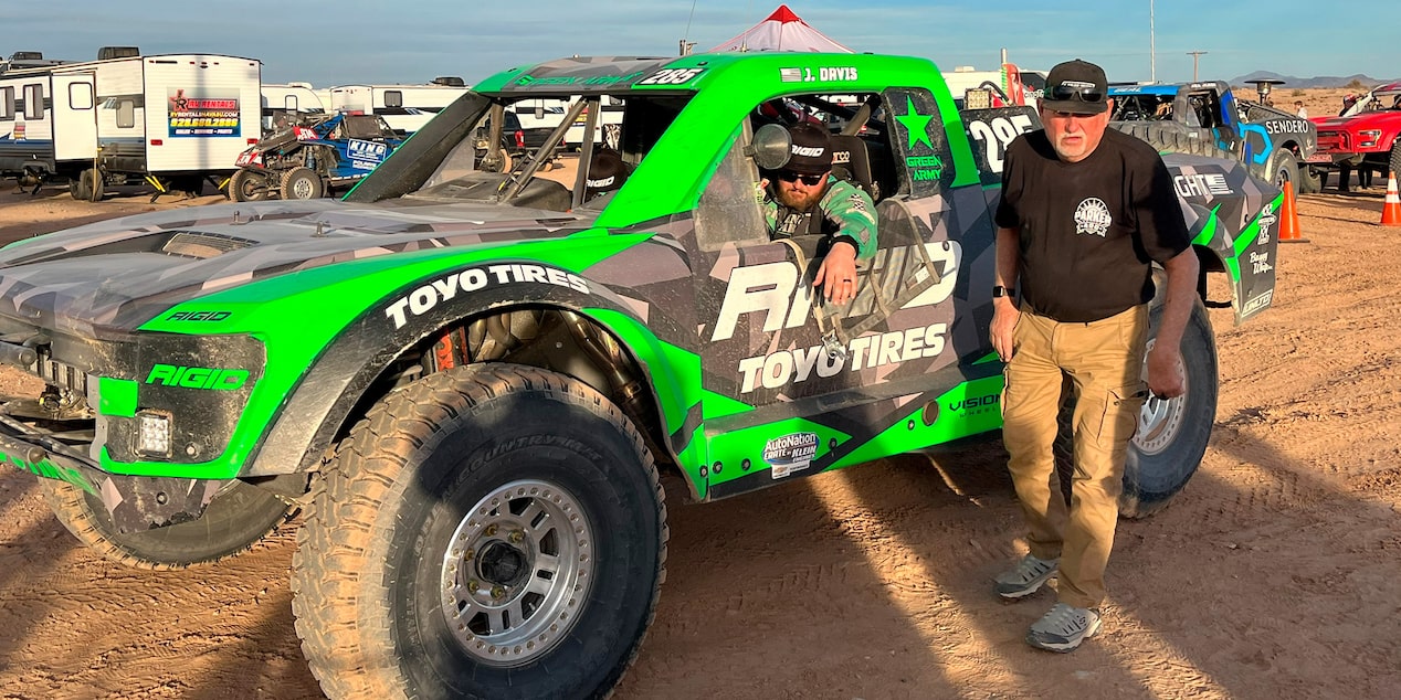 Man Standing Next to an Off-Roading Truck with the Driver Inside