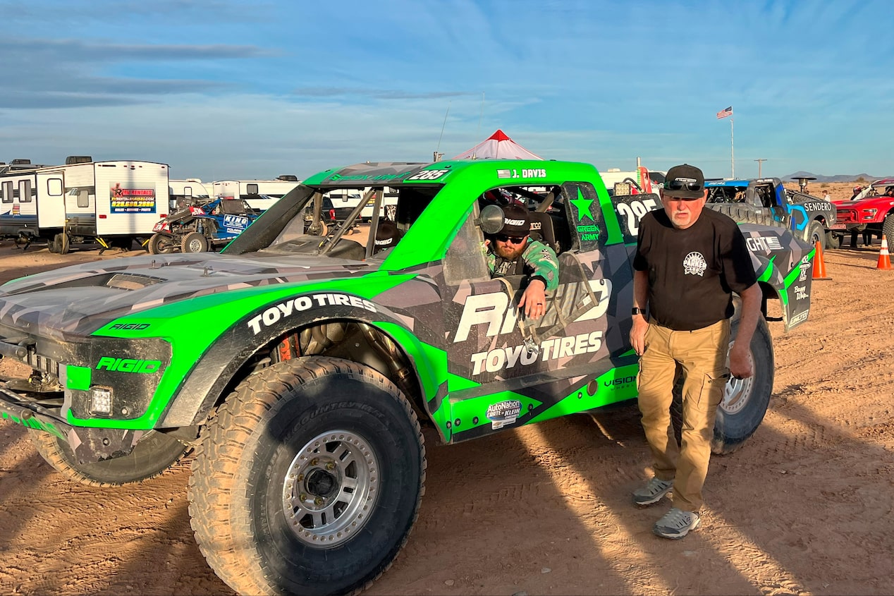 Man Standing Next to an Off-Roading Truck with the Driver Inside