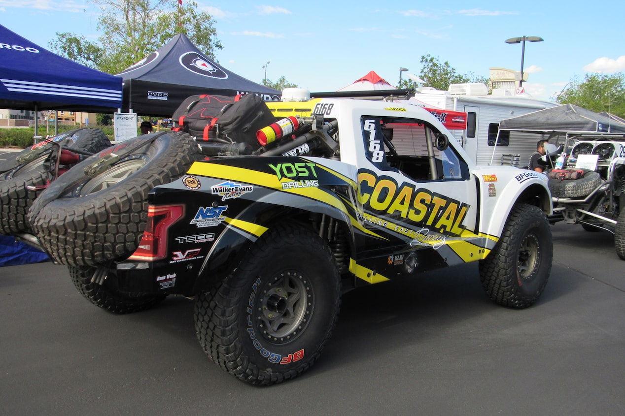 Left Rear View of a White Chevy Off-Roading Truck with Tires Loaded in the Truck Bed