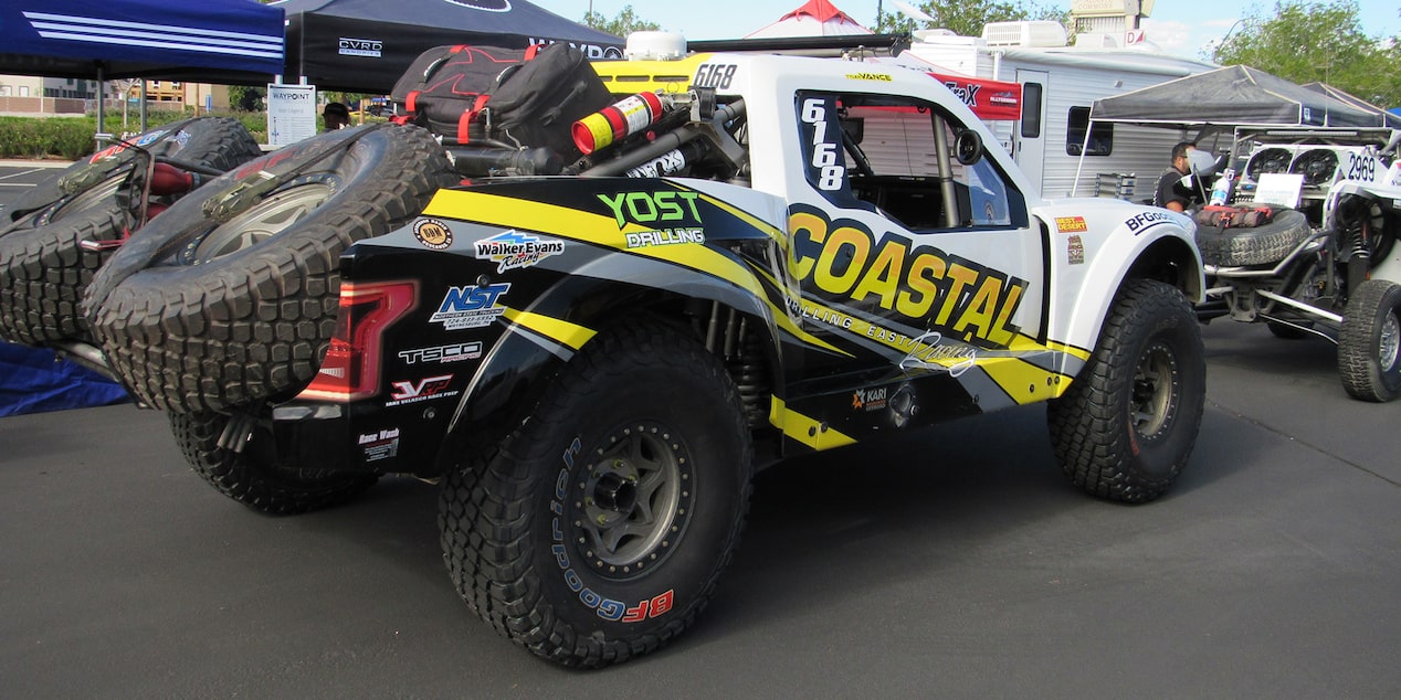 Left Rear View of a White Chevy Off-Roading Truck with Tires Loaded in the Truck Bed
