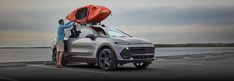 Hombre colocando un kayak en el techo de un vehículo Chevrolet