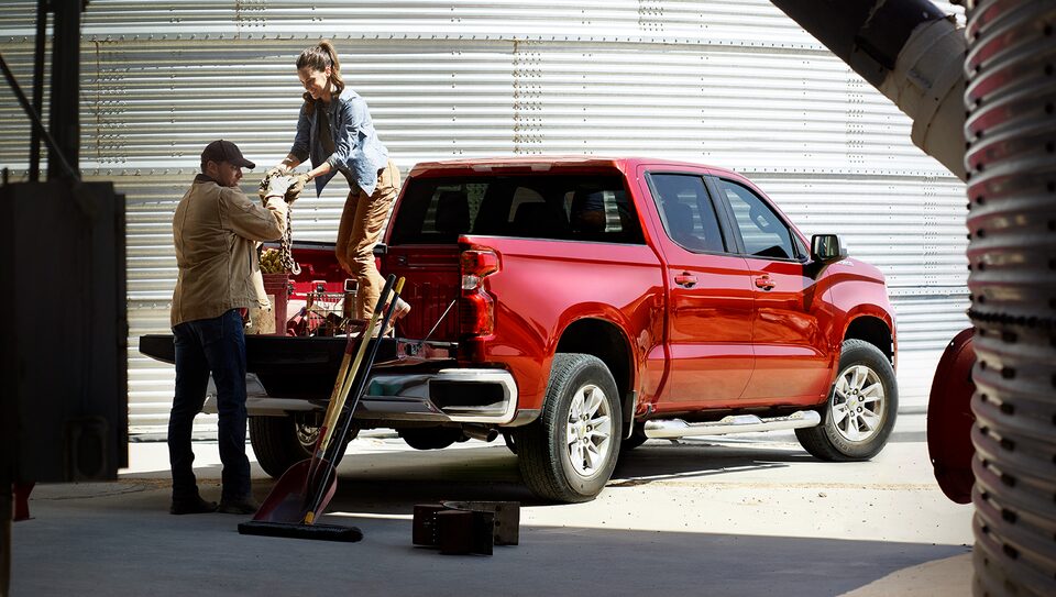 Trabajadores de campo descargando equipo de la caja de una camioneta Chevrolet Silverado