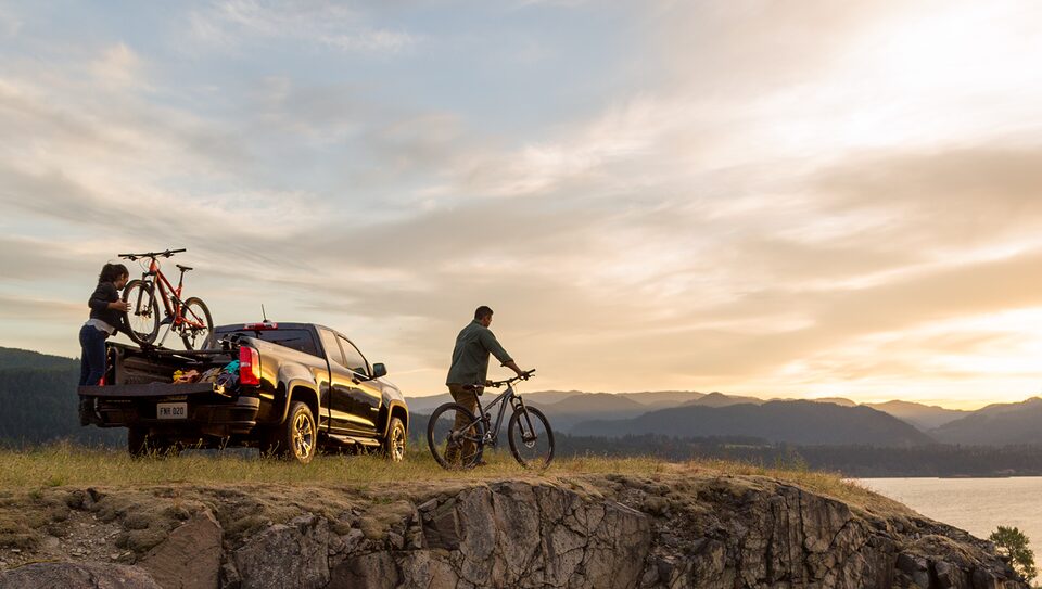 Pareja andando en bicicleta en la naturaleza con su camioneta Chevrolet Silverado