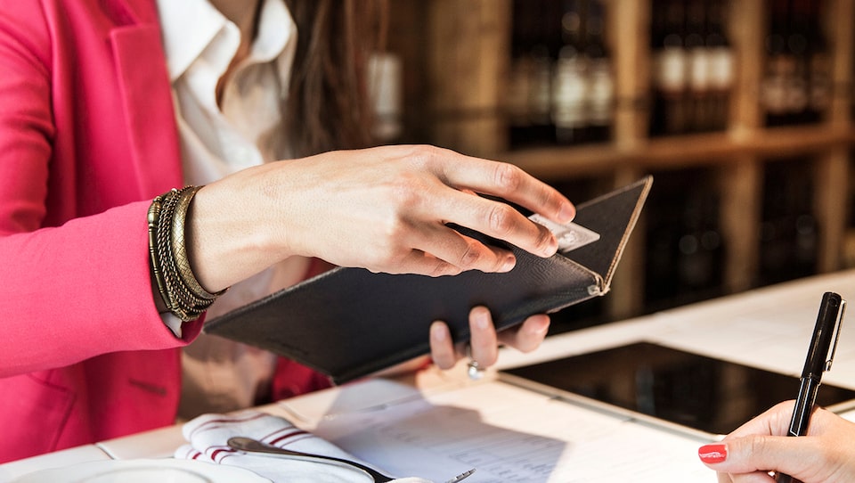 Mujer pagando la cuenta del restaurante con su tarjeta Mastercard comercial My Chevrolet Rewards