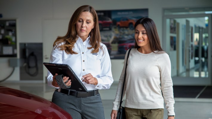 Dos mujeres paradas en frente de un vehículo Chevrolet