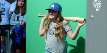 Niña posando con un bate de béisbol.