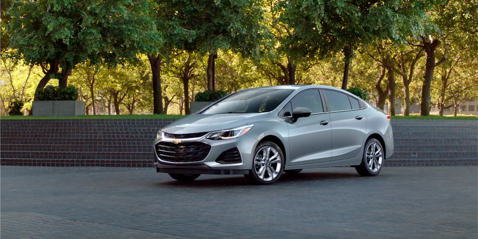 Vehículo GM Chevrolet estacionado cerca de una hilera de árboles