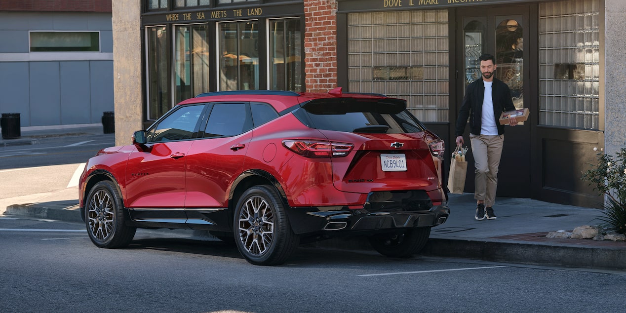 Man Walking Toward His 2026 Red Chevy Blazer Parked at a Shop