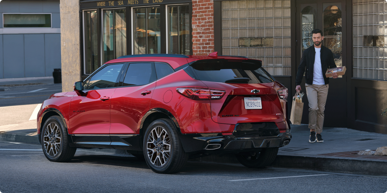 Man Walking Toward His 2026 Red Chevy Blazer Parked at a Shop