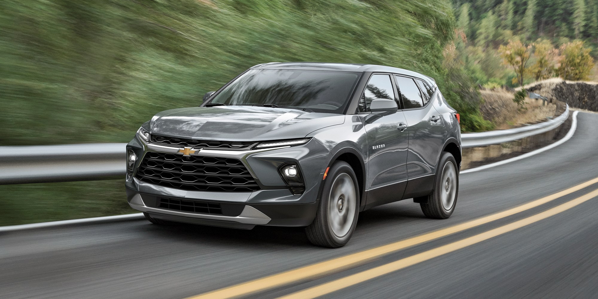 Gray 2026 Chevy Blazer Driving Swiftly on a Treelined Road