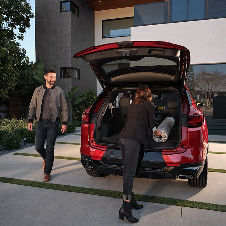 A Woman Putting a Mat Inside the Trunk of a 2026 Red Chevy Blazer