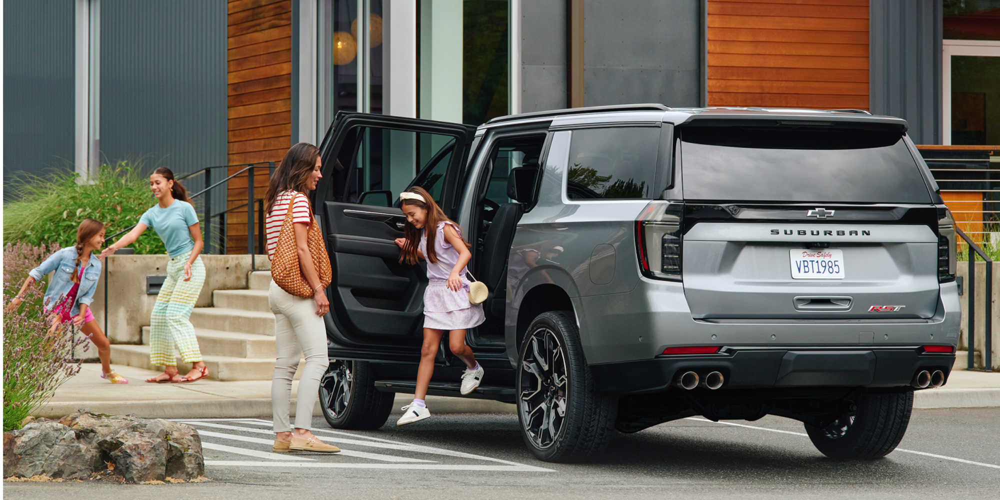 Rear Three-quarters View of a Family Getting Out of a 2026 Chevy Suburban