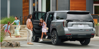 Rear Three-quarters View of a Family Getting Out of a 2026 Chevy Suburban