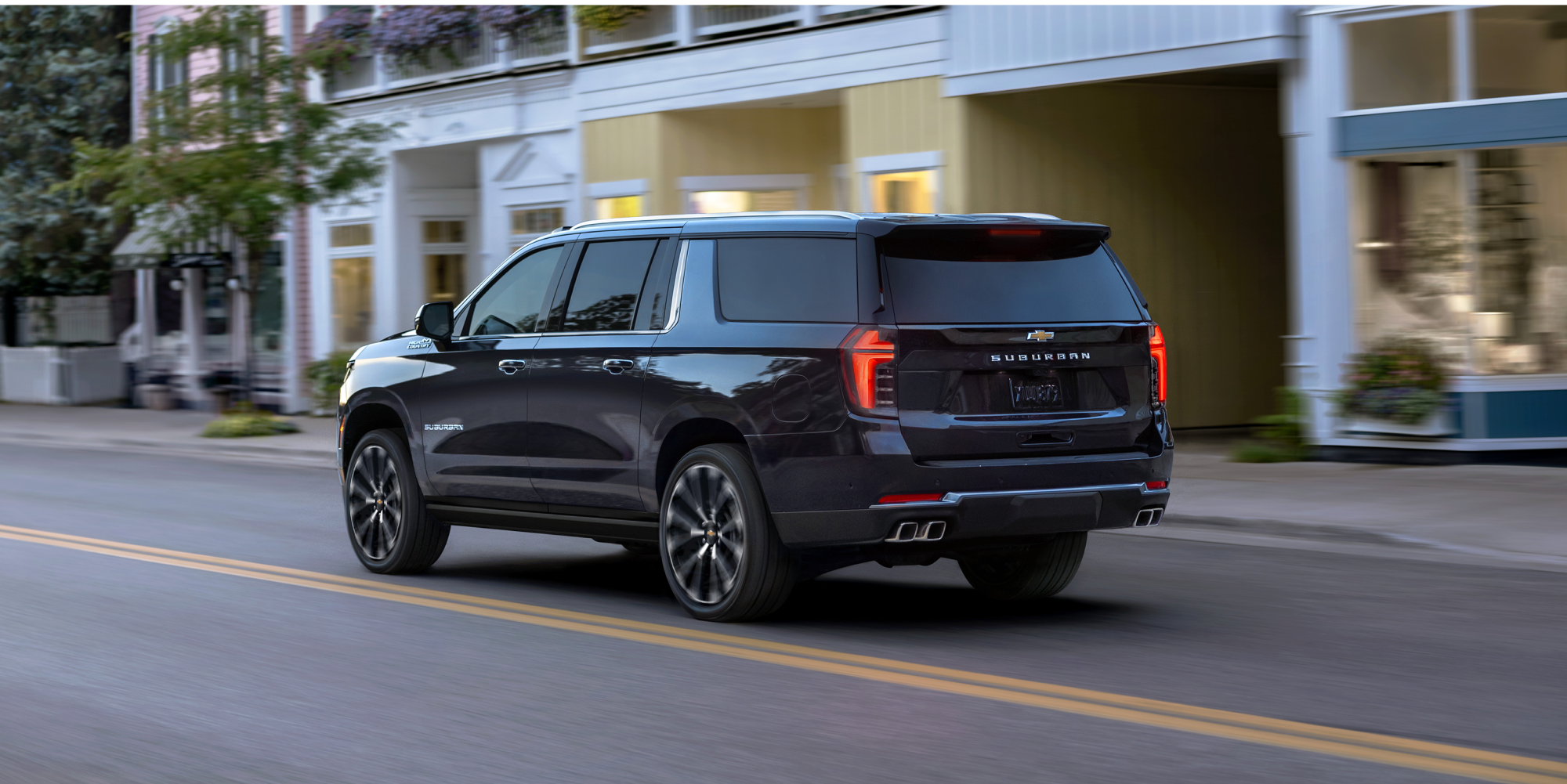 Rear Three-quarters View of the 2026 Chevy Suburban SUV Driving Through the City