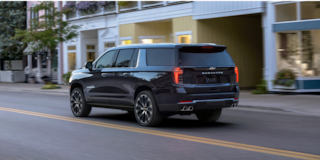 Rear Three-quarters View of the 2026 Chevy Suburban SUV Driving Through the City