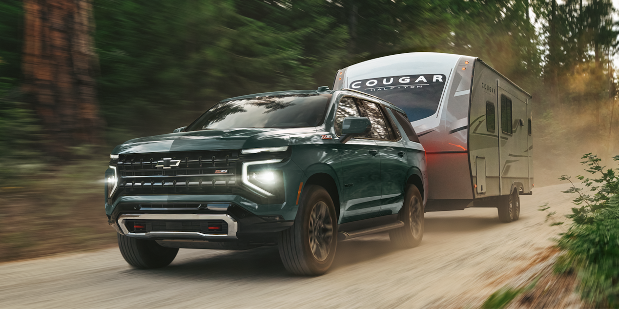 A 2026 Chevy Tahoe Hauling a Trailer on a Dirt Road Through the Woods