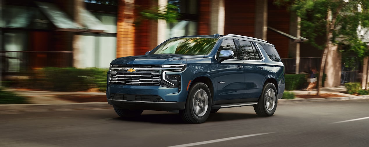 Three-quarter View of a 2026 Chevy Tahoe Driving Past a Brick Building