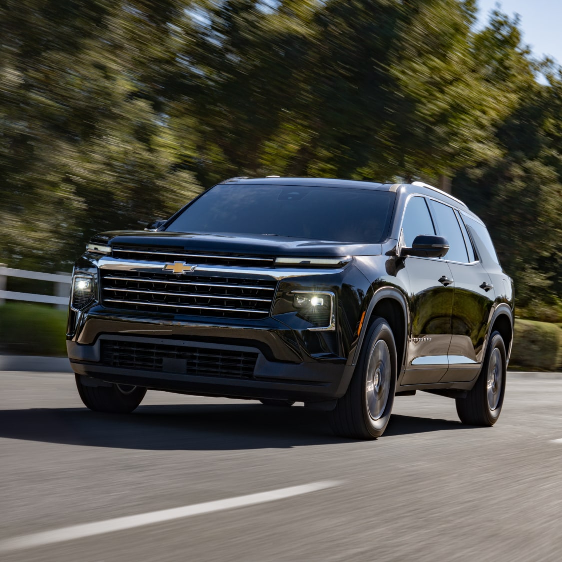 A 2027 Chevy Traverse Driving on a Road Featuring Distinctive LED Lighting and a Bold Front Grille Design.