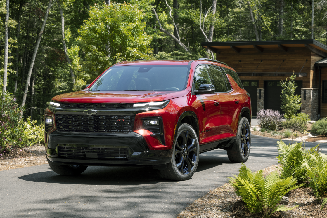 A 2027 Chevy Traverse Parked Outside a Cabin Surrounded by Trees and Natural Scenery.