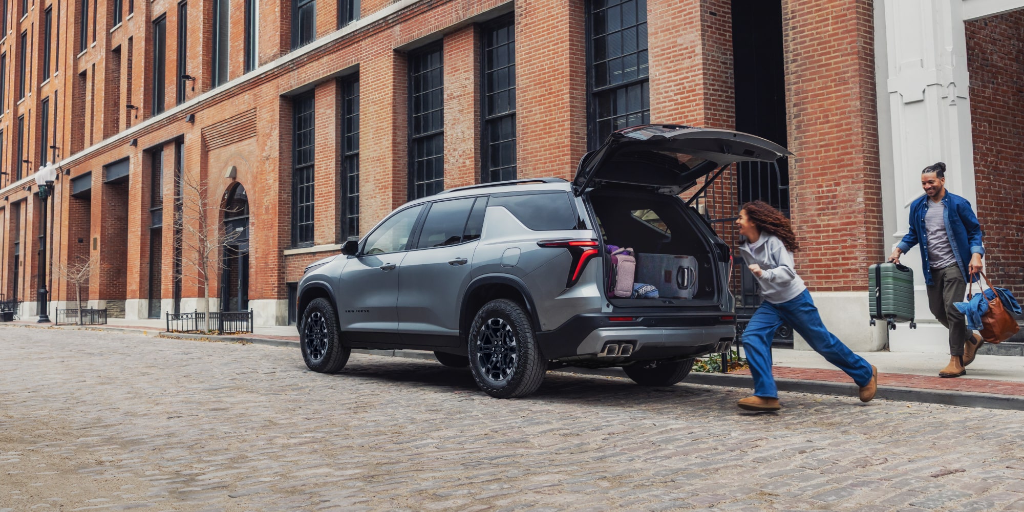 A 2027 Chevy Traverse Parked on a City Street With the Rear Liftgate Open for Cargo Loading and Unloading.