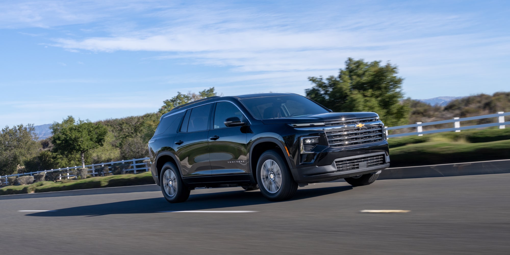 A 2027 Chevy Traverse Driving on a Road Showcasing a Strong Side Profile and Bold Front-End Styling.