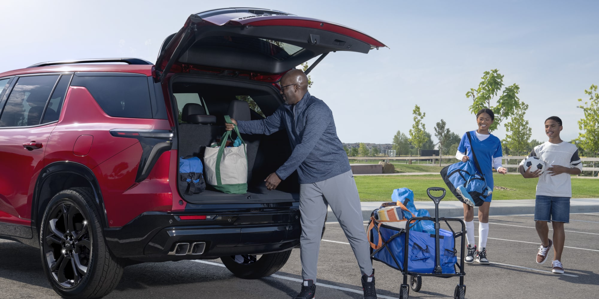 A 2027 Chevy Traverse Parked With the Rear Liftgate Open While Loading Cargo in an Outdoor Setting.