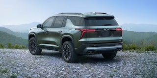 A 2027 Chevy Traverse Parked at a Scenic Overlook With Mountain Views Visible From a Rear Three-Quarter Angle.
