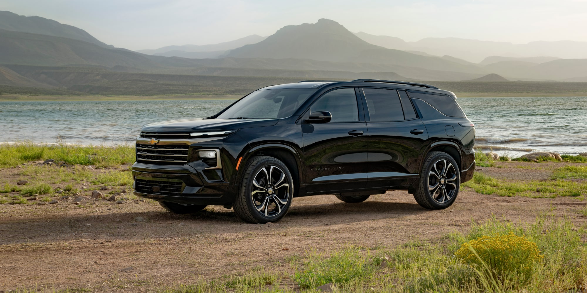 Profile View of an All-black 2027 Chevy Traverse Parked Next to a Lake by the Mountains