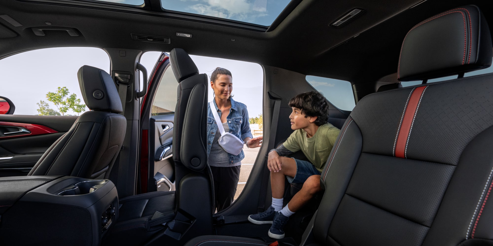 A Person Entering the Third-Row Seating Area of a 2027 Chevy Traverse Featuring Flexible Passenger Access and a Spacious Interior Layout.