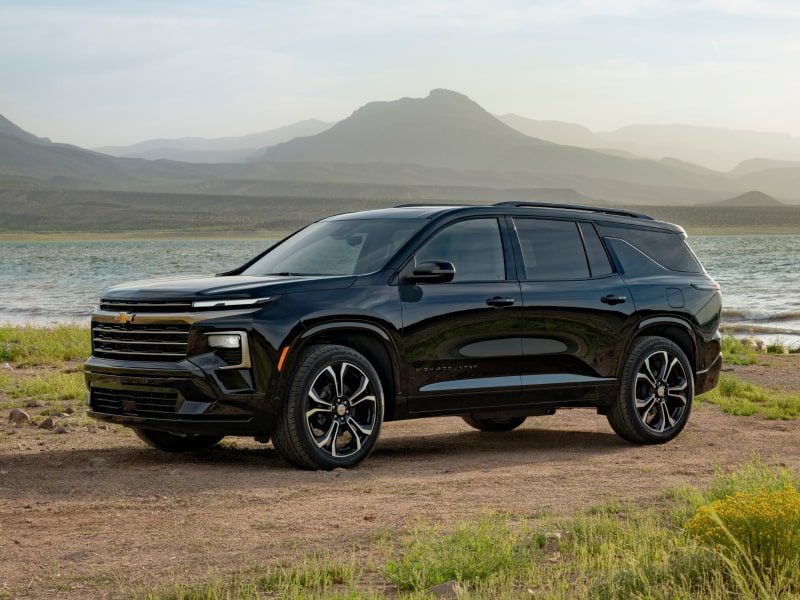 Profile View of an All-black 2027 Chevy Traverse Parked Next to a Lake by the Mountains