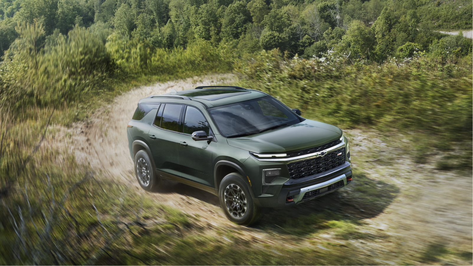 A 2027 Chevy Traverse Driving Along a Dirt Road Through a Natural Landscape.