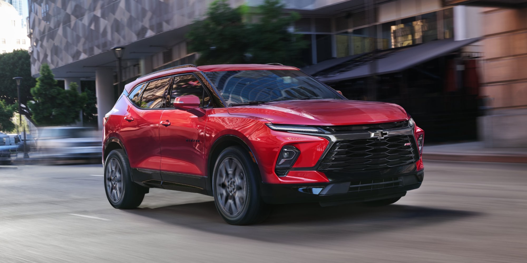 Three-quarters View of a Red Chevy Blazer Driving Through a Downtown City