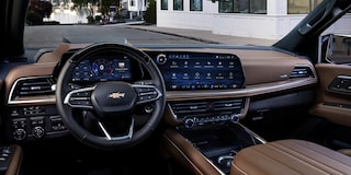 The Driver’s View Inside a Chevrolet Suburban Featuring a Leather-Wrapped Steering Wheel, a Digital Gauge Cluster, and a Wide Touchscreen Display.