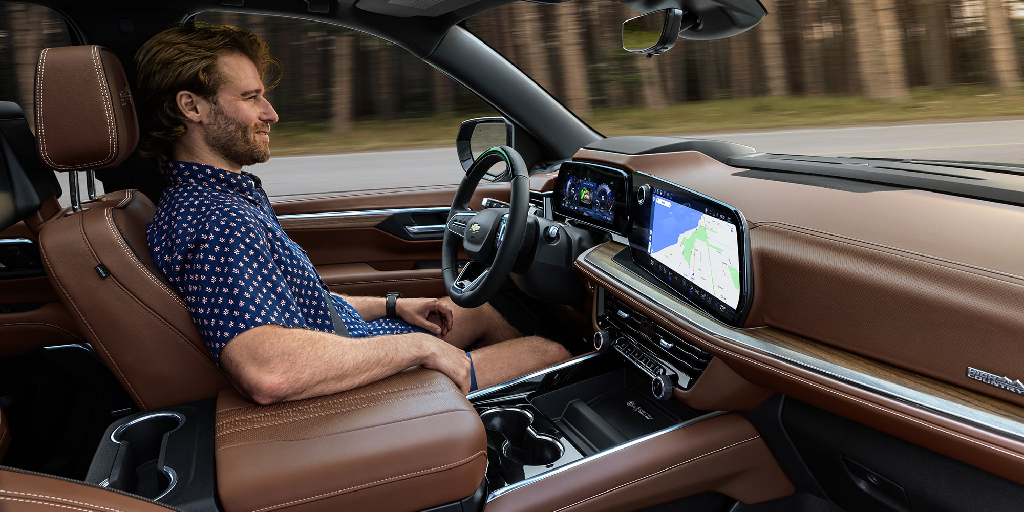 The Interior of a Chevrolet Suburban Showing a Driver Using the Center Touchscreen and Sitting in a Premium Leather Cabin.