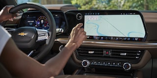 A Driver Inside a Chevrolet Tahoe Using the Large Central Touchscreen Display While Navigating a Map Interface.