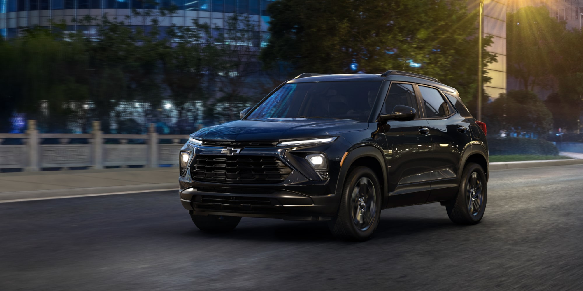 Una Chevrolet Trailblazer circulando por la calle de una ciudad con edificios modernos y árboles verdes en el fondo.