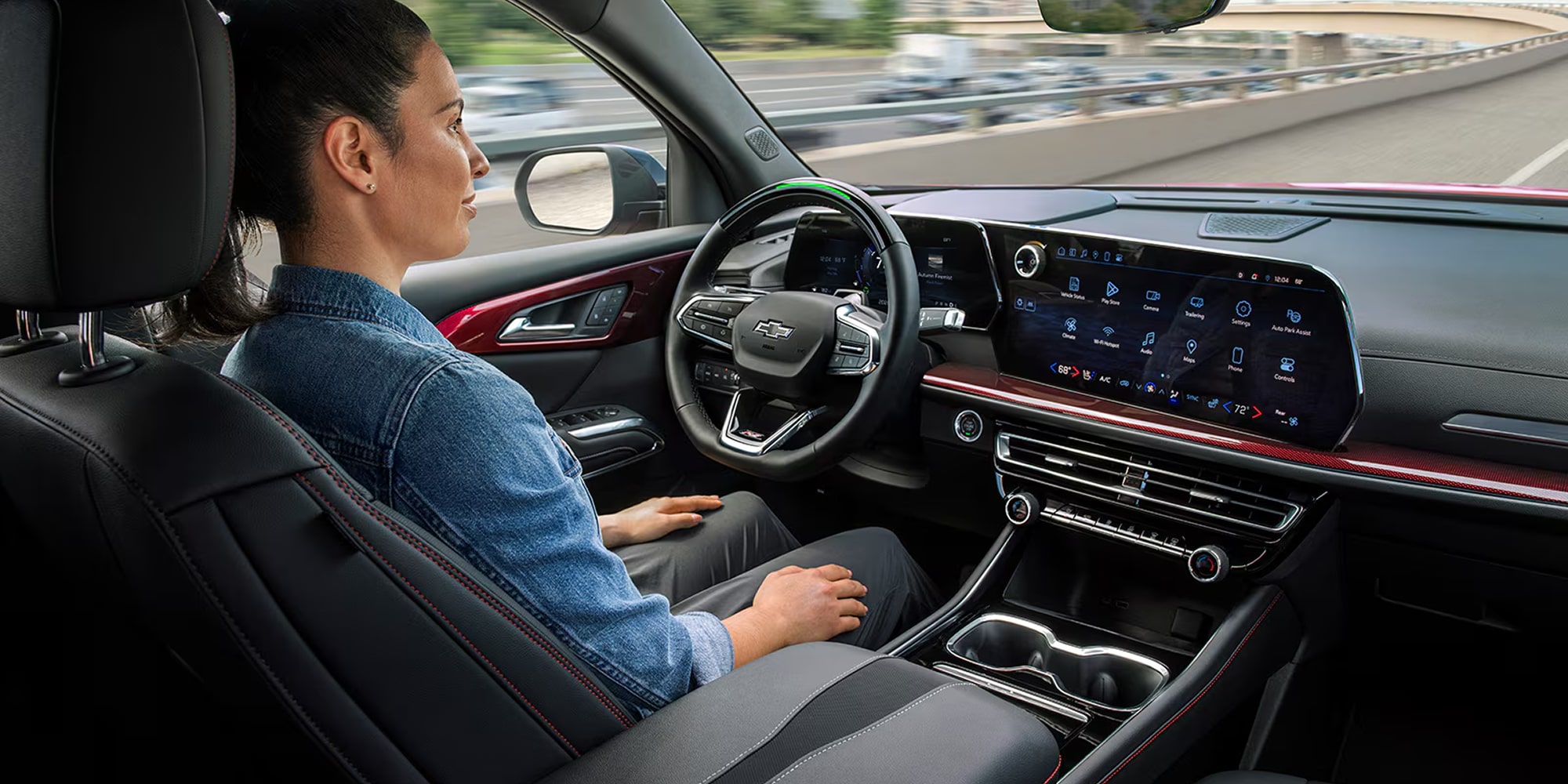 The Interior of a Chevy Traverse Displaying a Wide Digital Dashboard, a Leather‑Wrapped Steering Wheel, and Seats With Sleek Black and Red Accents.