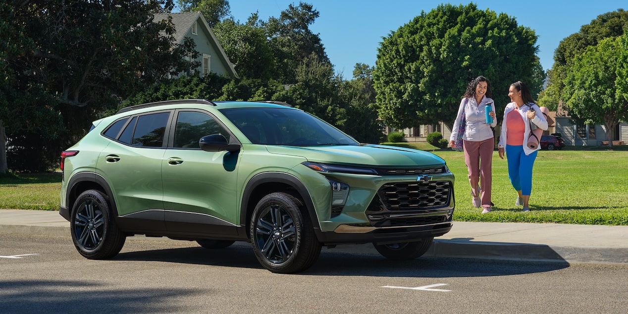 Two Women with a Yoga Mat and Water Bottle Walking Towards a Parked Chevrolet Trax near a Urban Neighborhood