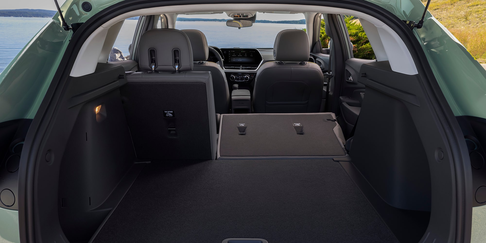 El área de carga de un Chevrolet Trax, mostrando los asientos traseros plegados y un compartimento de almacenamiento amplio y abierto visto desde la compuerta trasera.