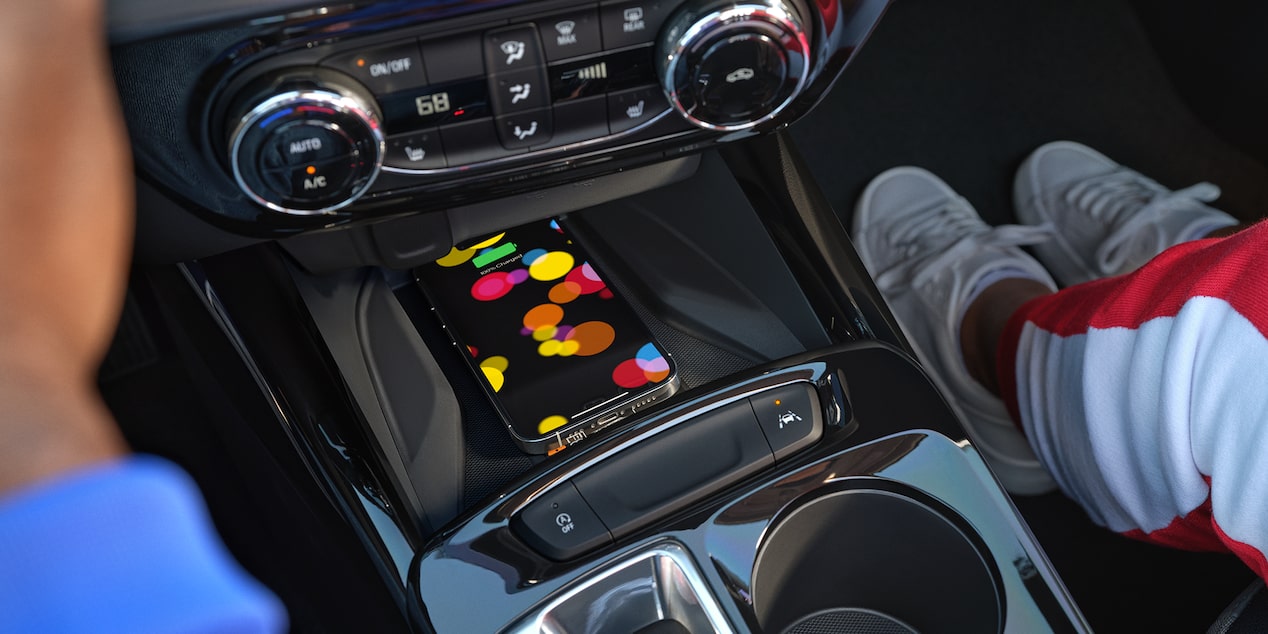 A Smartphone Displaying a Colorful Screen Resting on the Wireless Charging Pad Within the Center Console of a Chevrolet Trax