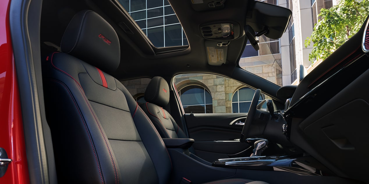 The Front Row Interior Cabin of a Chevrolet Trax Featuring Black Seats With Red Stitching, and a Panoramic Sunroof