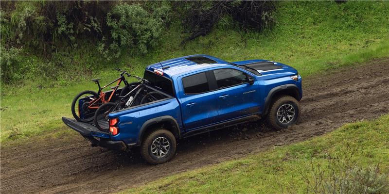 Side view of a 2026 Blue Chevy Colorado driving up a mountain