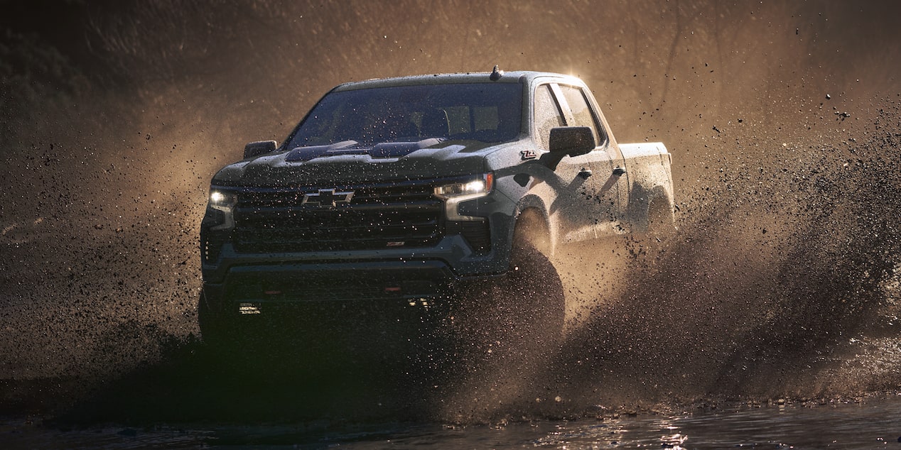 2026 Chevy Silverado Truck Driving Through Muddy Terrain with Splashes of Water