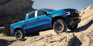 Blue 2026 Chevy Silverado Climbing a Rocky Hill Under Clear Blue Sky